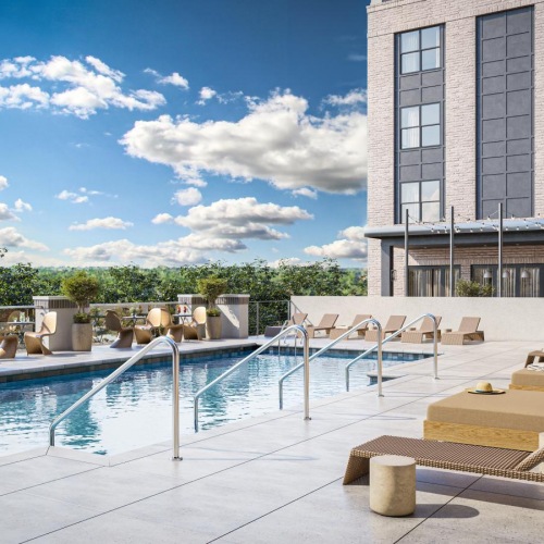Resort-style swimming pool a pool with chairs and tables next to a building