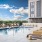 a pool with chairs and tables next to a building